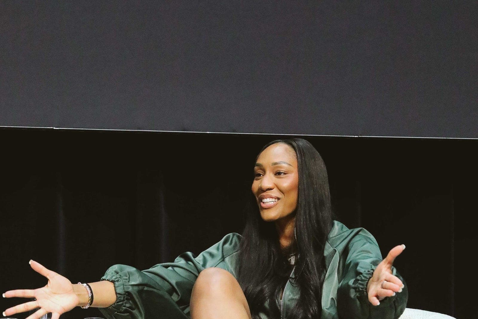 A'ja Wilson seated on stage during a live podcast taping