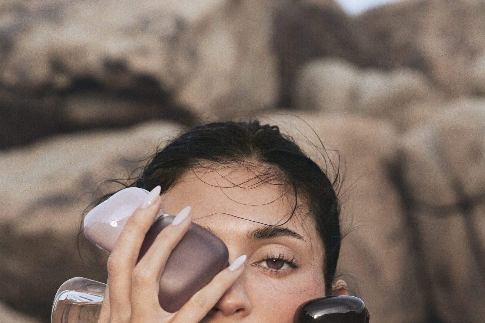 Kylie Jenner holding several sculptural perfume bottles from the Mood Stones collection