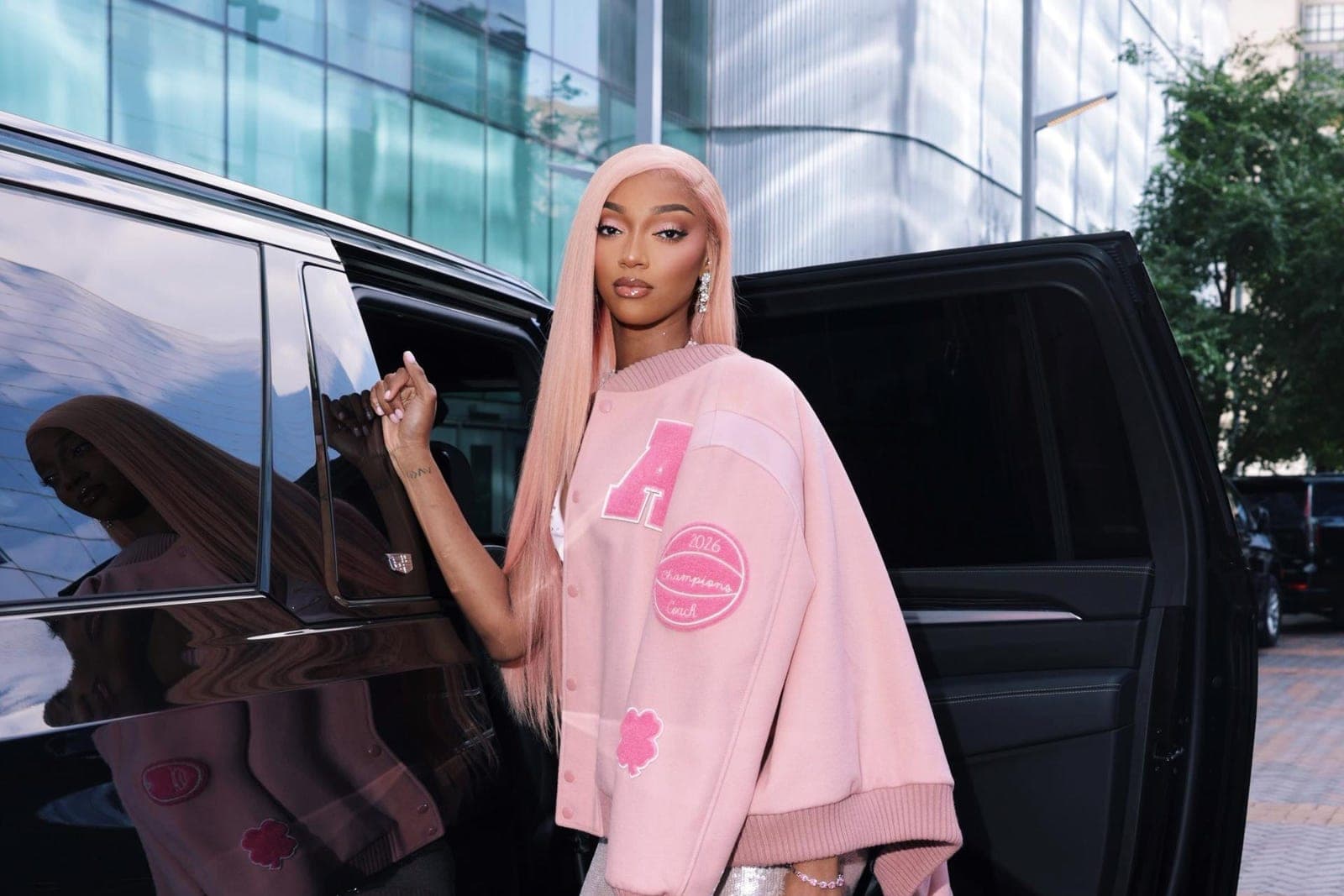A WNBA player arriving at All-Star weekend in a pink jacket and skirt