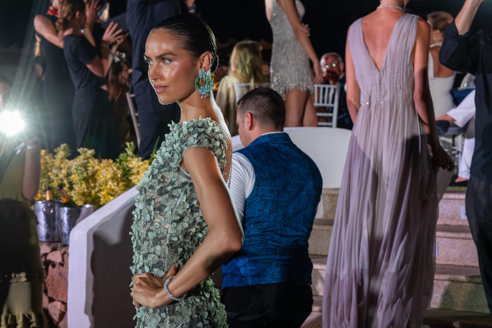 A model in an embellished gown wearing emerald and diamond Chopard earrings